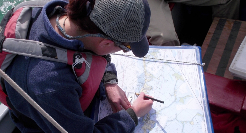 A person wearing a life jacket examines a map. 